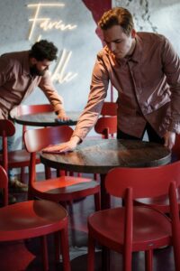 Man in Brown Leather Jacket Holding Brown Wooden Round Table